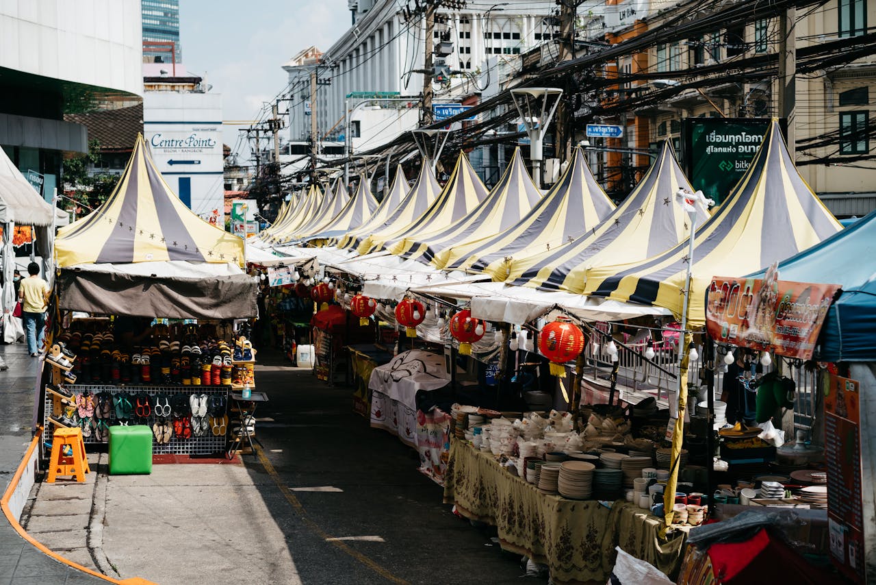 Explore the bustling atmosphere of a Bangkok street market, adorned with yellow tents and colorful stalls.