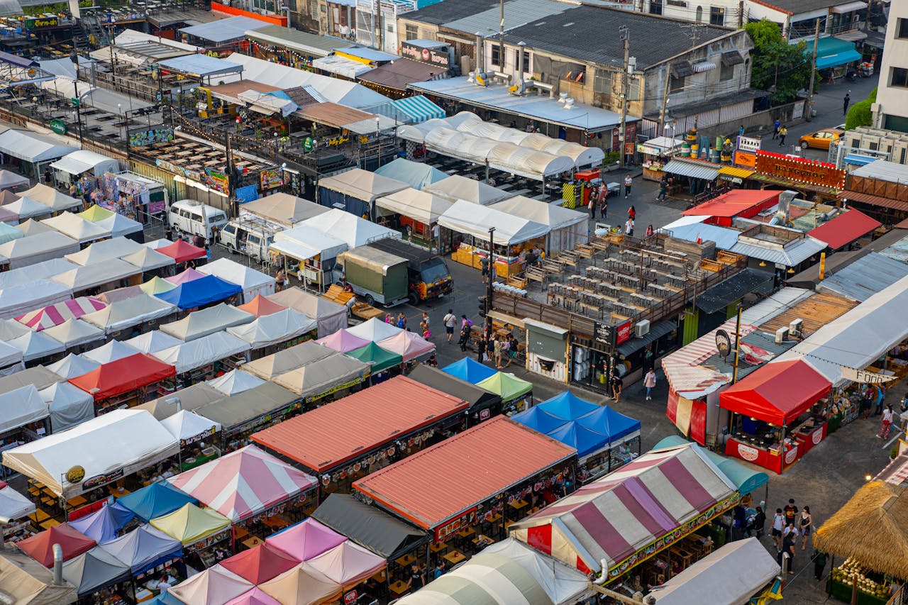 Colorful aerial view of bustling market stalls with diverse canopies and people shopping.